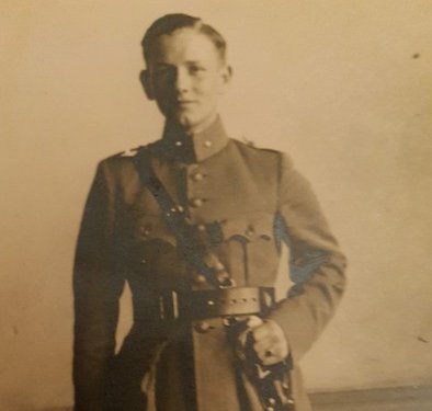 Sepia foto van Dordtse verzetsstrijder Kees Oversier ten voeten uit. Hij draagt een uniform met in zijn hand een sabel.
