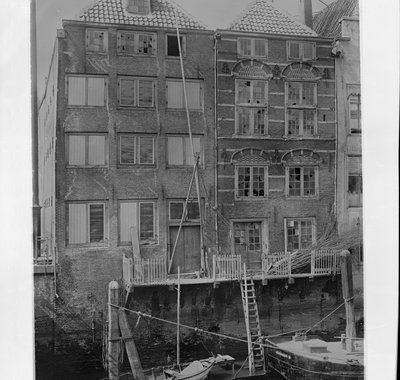 Achtergevels van de huizen aan het water. Er liggen twee bootjes in het water.