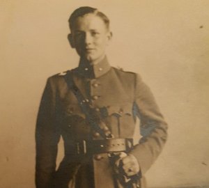 Sepia foto van Dordtse verzetsstrijder Kees Oversier ten voeten uit. Hij draagt een uniform met in zijn hand een sabel.