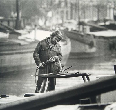 Man in overal is in de jachthaven aan het werk.