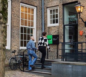 Man en vrouw lopen het trapje op naar de deur van de Studiezaal van het Regionaal Archief Dordrecht.