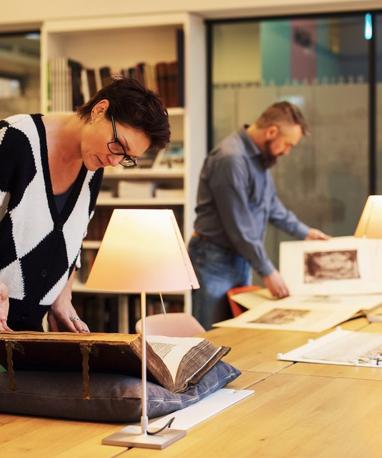 Man en vrouw in de Studiezaal van het Regionaal Archief Dordrecht. Ze staan aan tafel en bestuderen archiefstukken.